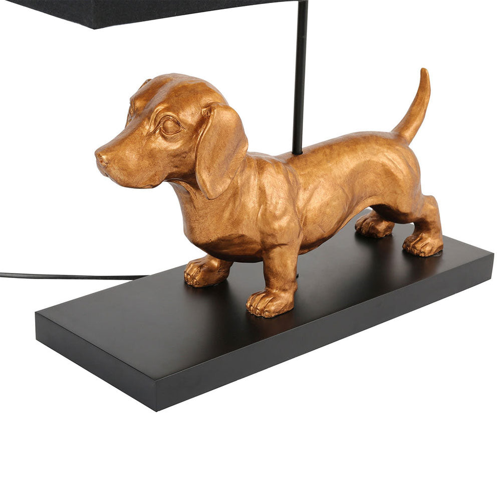 Gold dog-shaped lamp on a black base with a white background