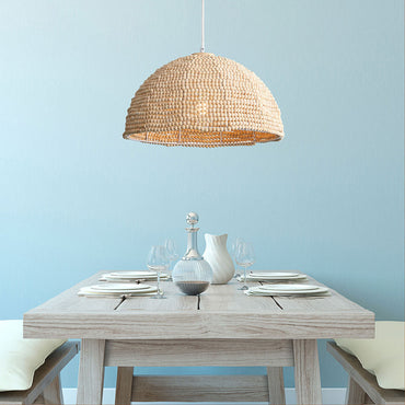 Dining table set with a woven pendant light against a light blue wall.