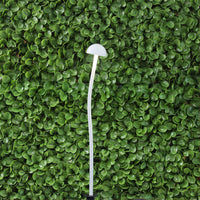 White mushroom-shaped light on a green leafy background