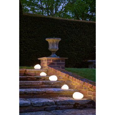 Glowing spherical lights on stone steps with a decorative urn in a garden setting.